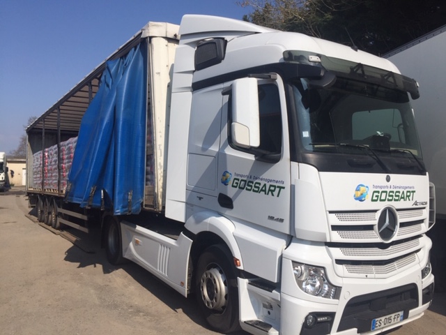 Camion Gossart avec du matériel dans la remorque et bâche bleue repliée sur le côté